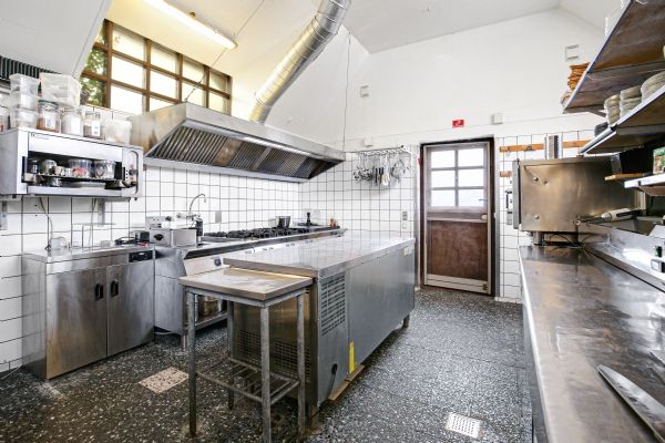 Stålkøkken med vinduesudsigter, store apparater og ren gulvoverflade, der er ideelt til kulinariske oplevelser og madlavning