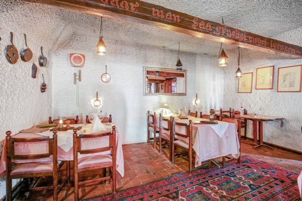 En hyggelig, simpel restaurant med lyserøde stole, hvide duge, og lyse lamper hængende fra loftet.