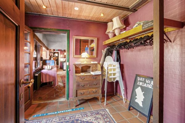 Værelse med møbler og tøjreol, der er klædt i lysebrune vægge og træloft, med lysekroner og et skrivebord med lamper og spejl