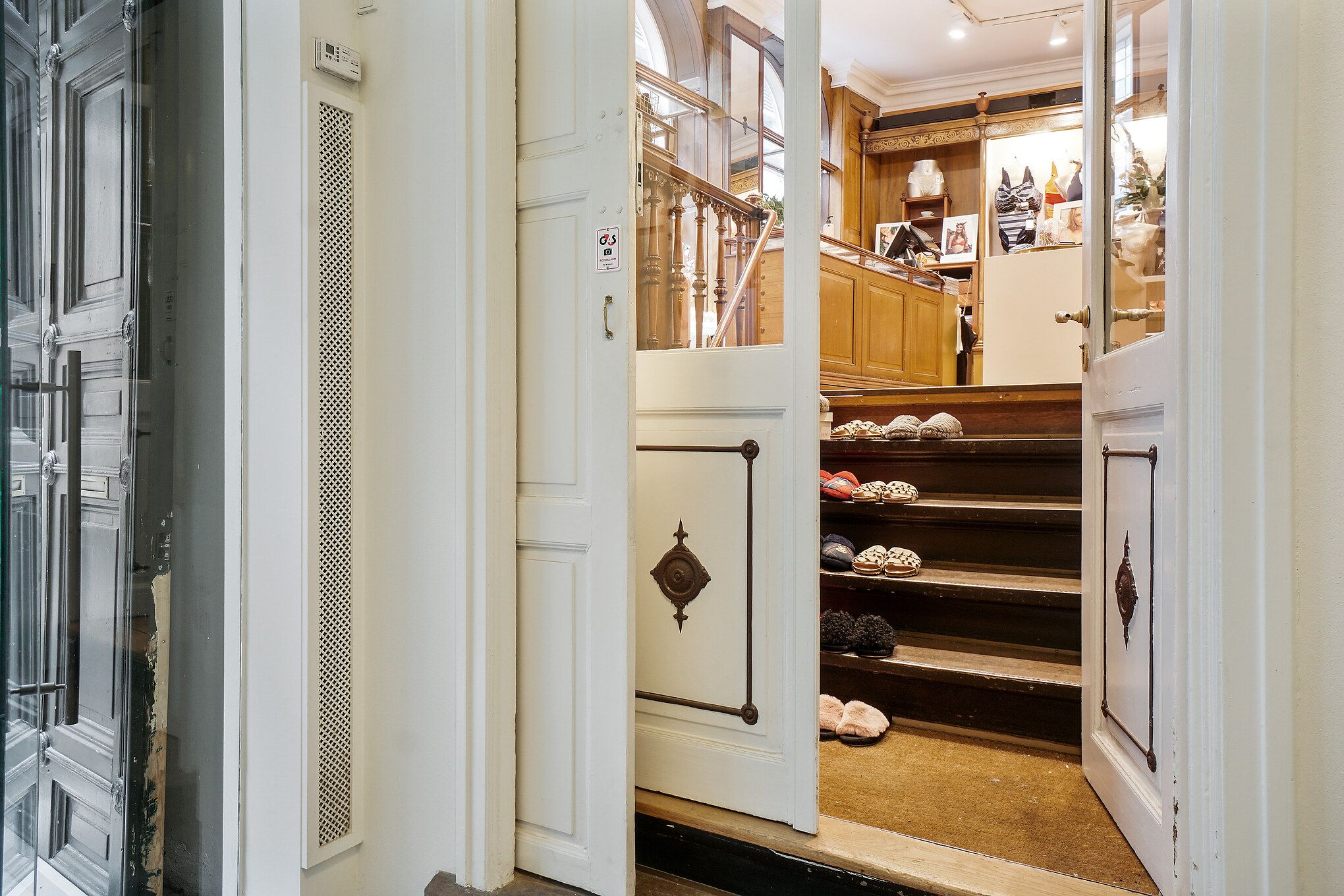 Restaurant med åben dør og trapper med sko og tæpper. Der er et gulv og en garderobe med tøj og figurer.