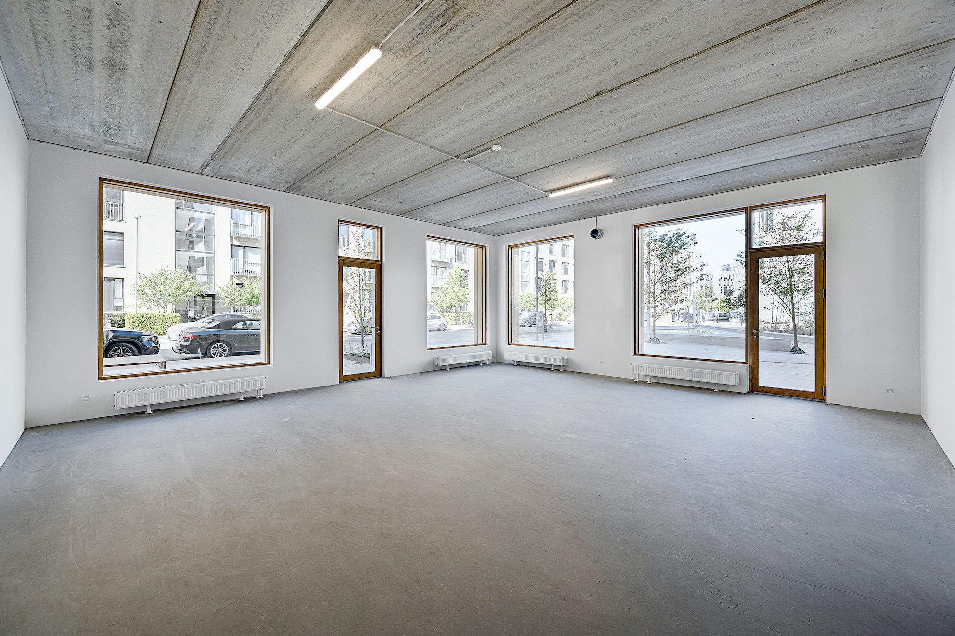 Store, hvide lokaler med højt til loftet og lyse vinduer med udsigt til gården og biler.