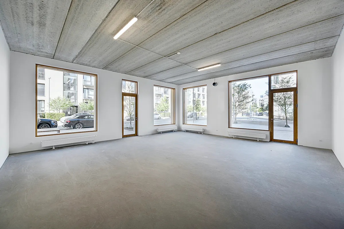 Store, hvide lokaler med højt til loftet og lyse vinduer med udsigt til gården og biler.