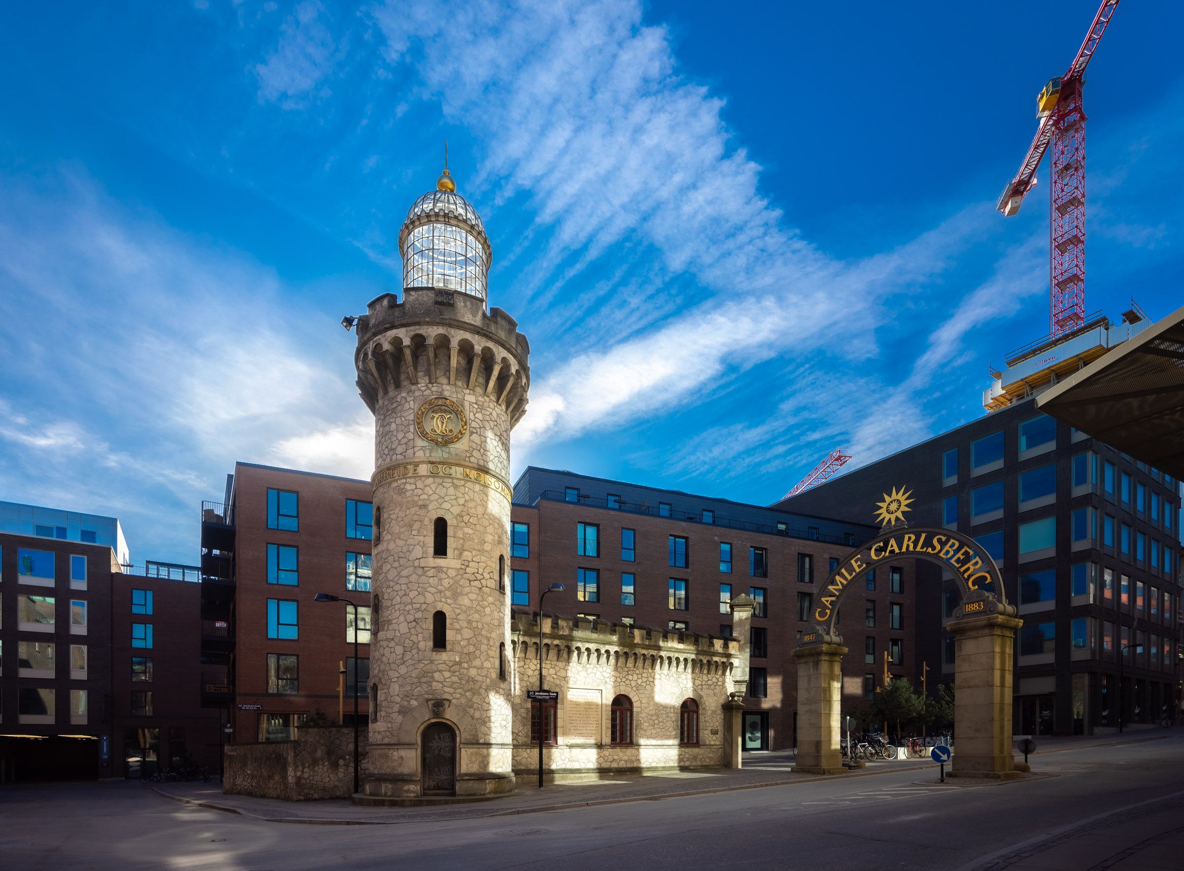 Lysthus med glaskuppel og ur på Carlsberg-grunden i København. Foran ligger Carlsberg-arkaden med en sol på skråt. Bygninger