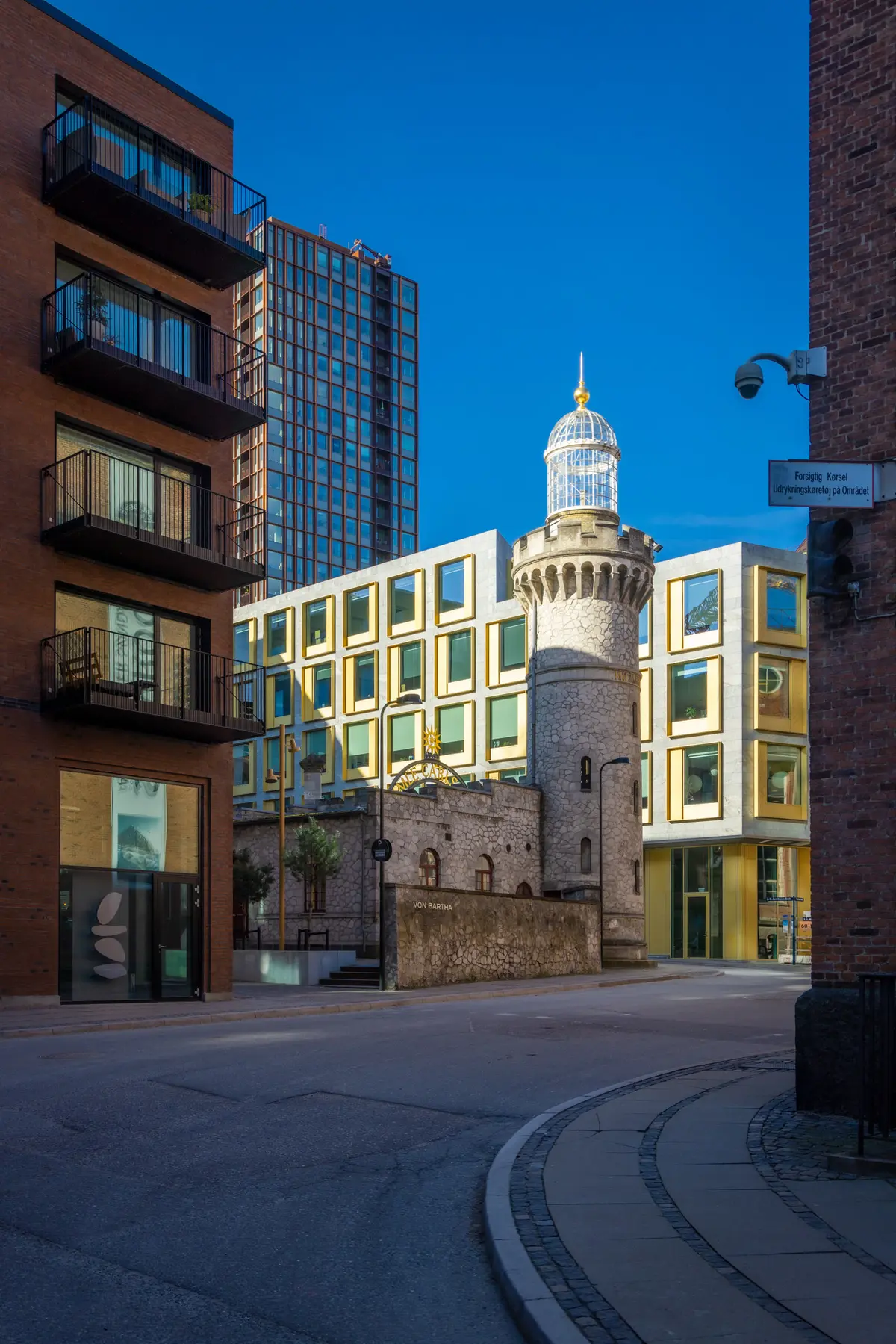 Store høje bygninger og tårn med gult facade og glasvinduer og lyse himmel i baggrunden