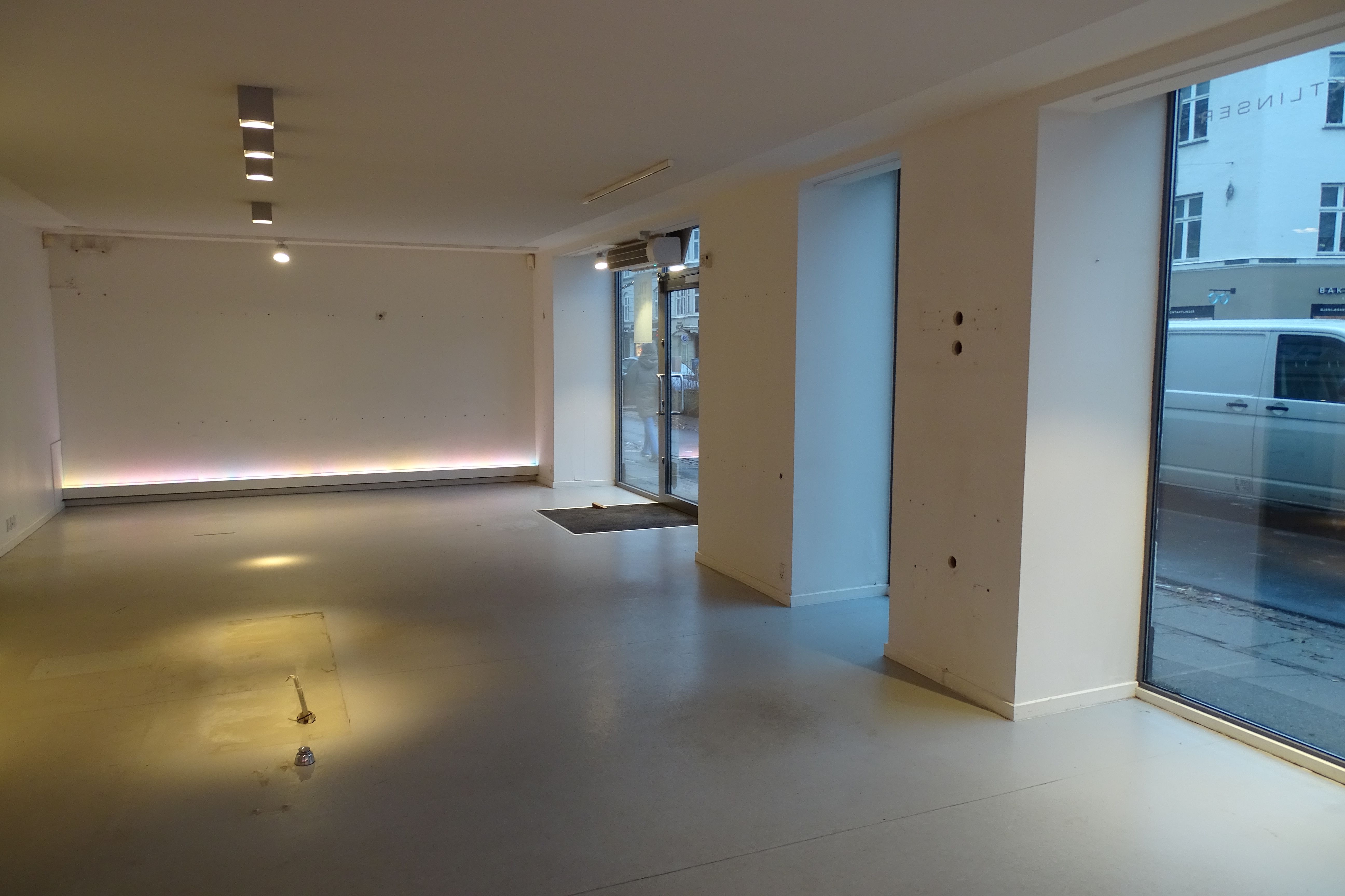 Store hvide lokaler med store vinduer og en udgangsdør til gadefortov med en forhøjning og gulvbelægning af marmor