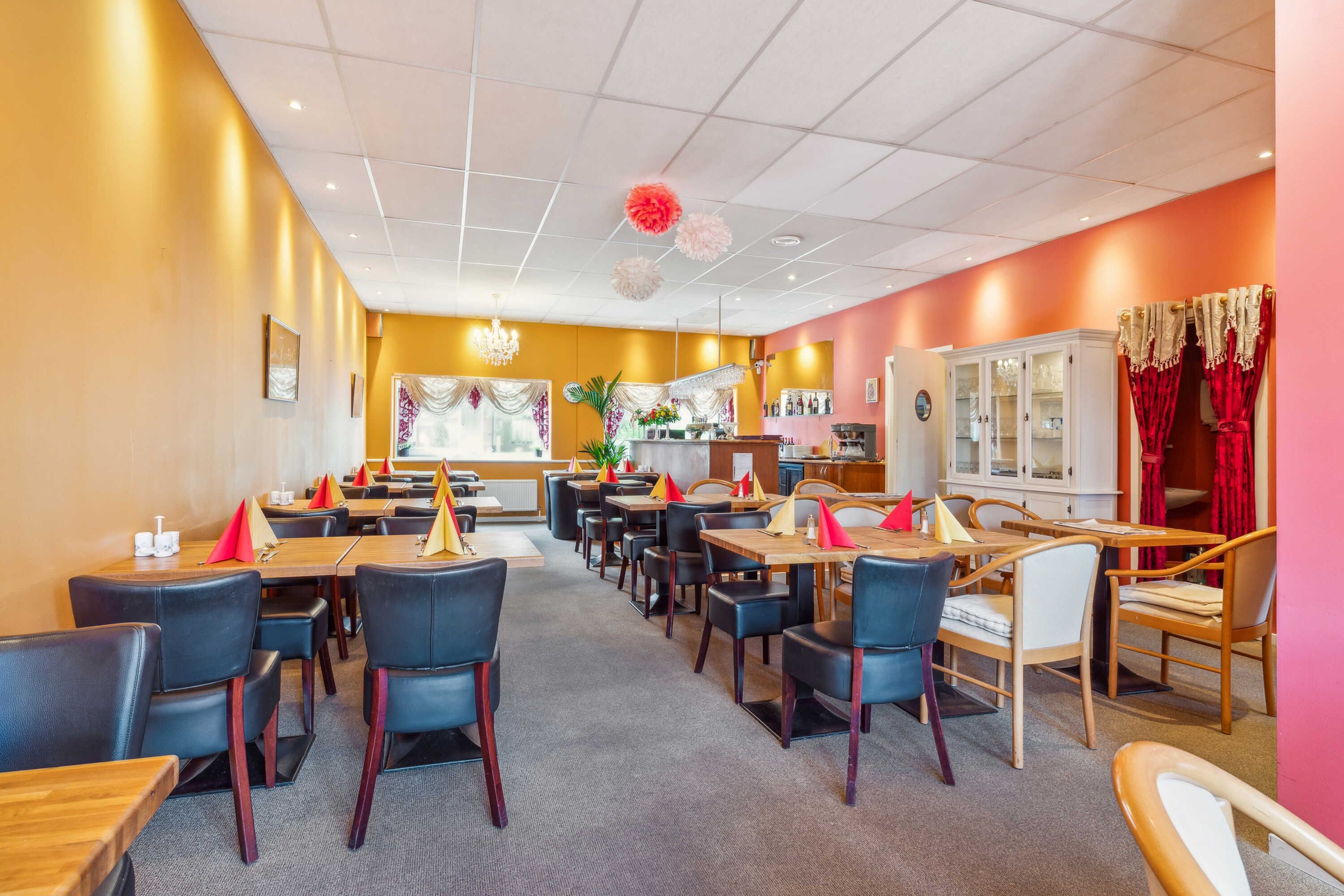 Indretning af et restaurant med bord og stole, smukt udsmykket med køkkenudstyr og lyse farver