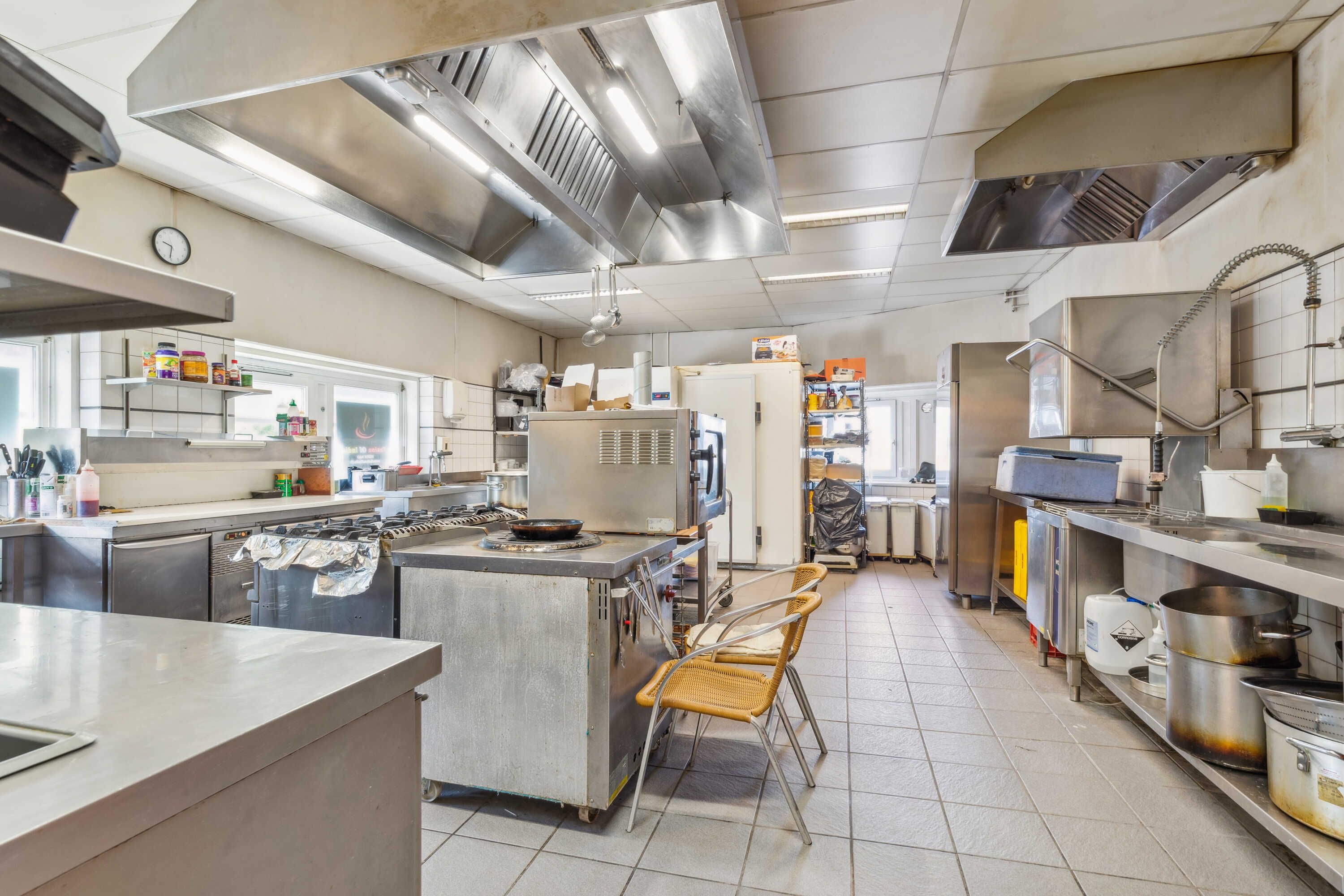 En indisk restaurant med en stor komfur, gaskomfur og ovn, samt en metalbord og stole, og en række apparater og