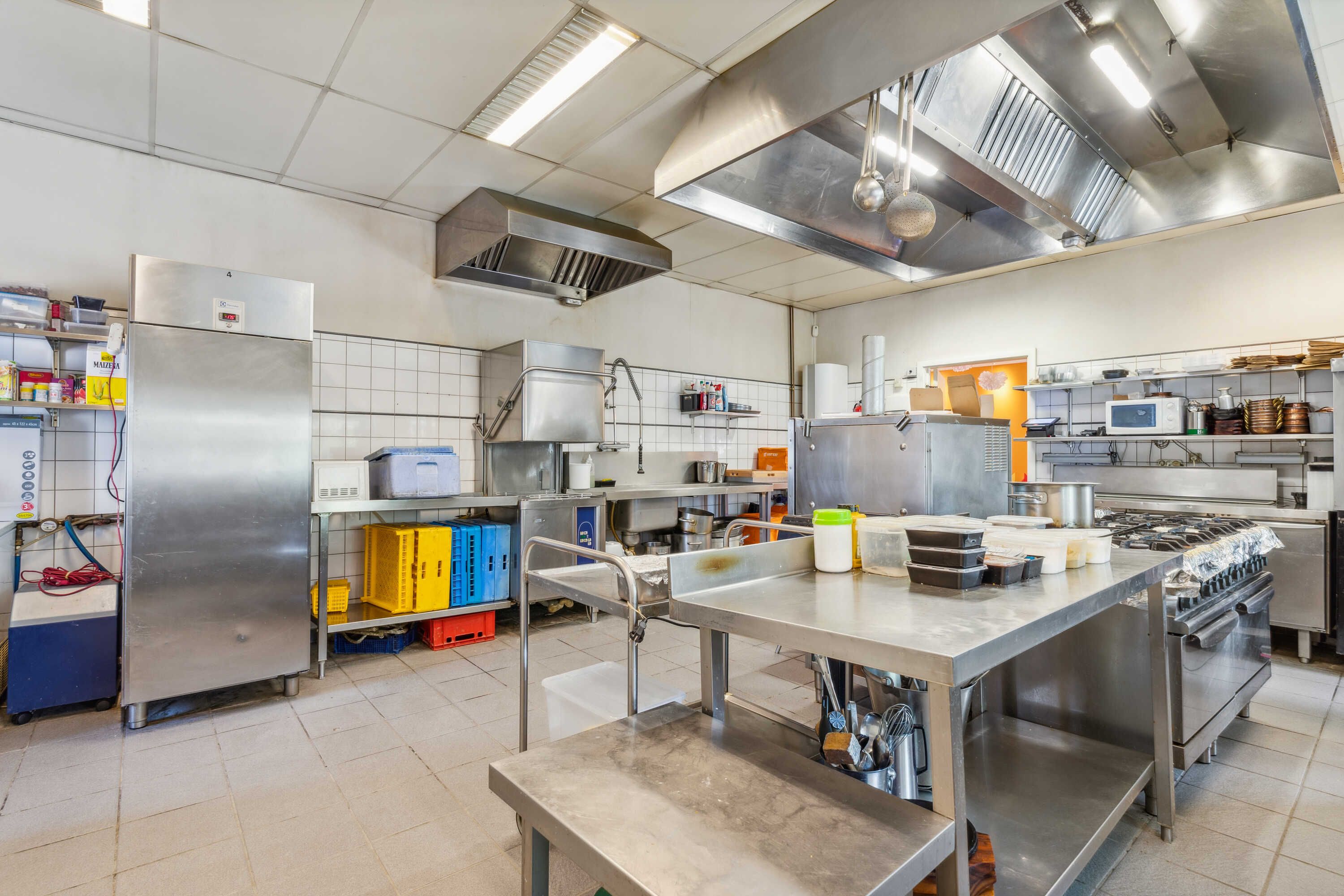 En kommerciel køkken med rustfrit ståludstyr, højt kvalitetsloft, og moderne ventilation. Forskellige apparater, udstyr og