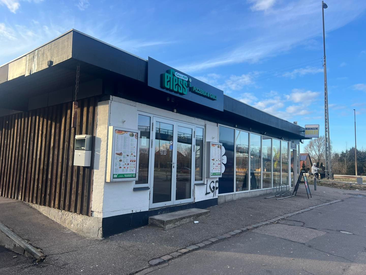 En pizzeria med navnet Efess Pizza & Grill ligger i en travl gade med glasruder og vinduer