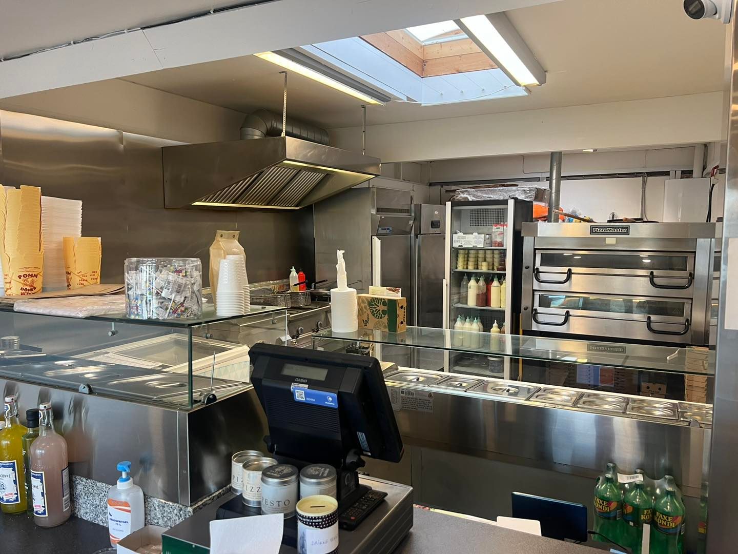 Pizzeria med flere ovne, køleskabe, flasker, sælger varer og drik og sælges til spotpris