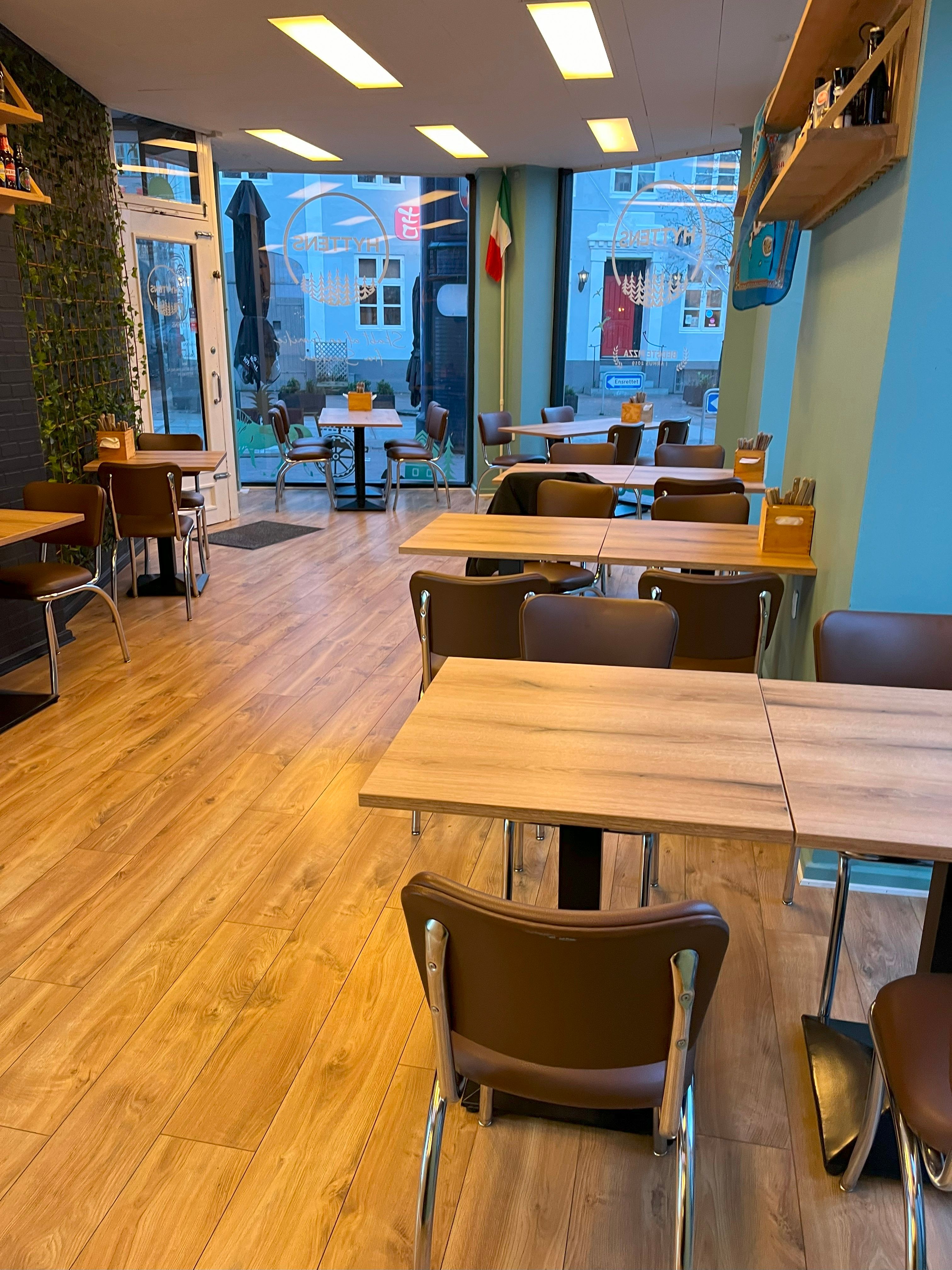 Indvendørs billede af en moderne restaurant med lysegul gulvbelægning og møbler, herunder borde og stole i brunt og lysegråt