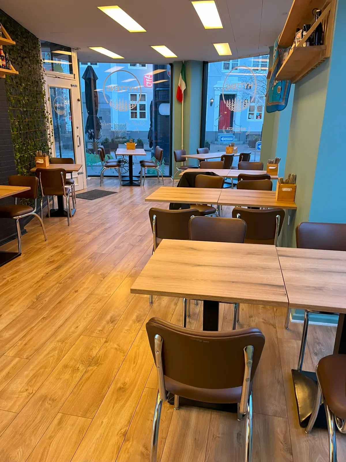 Indvendørs billede af en moderne restaurant med lysegul gulvbelægning og møbler, herunder borde og stole i brunt og lysegråt