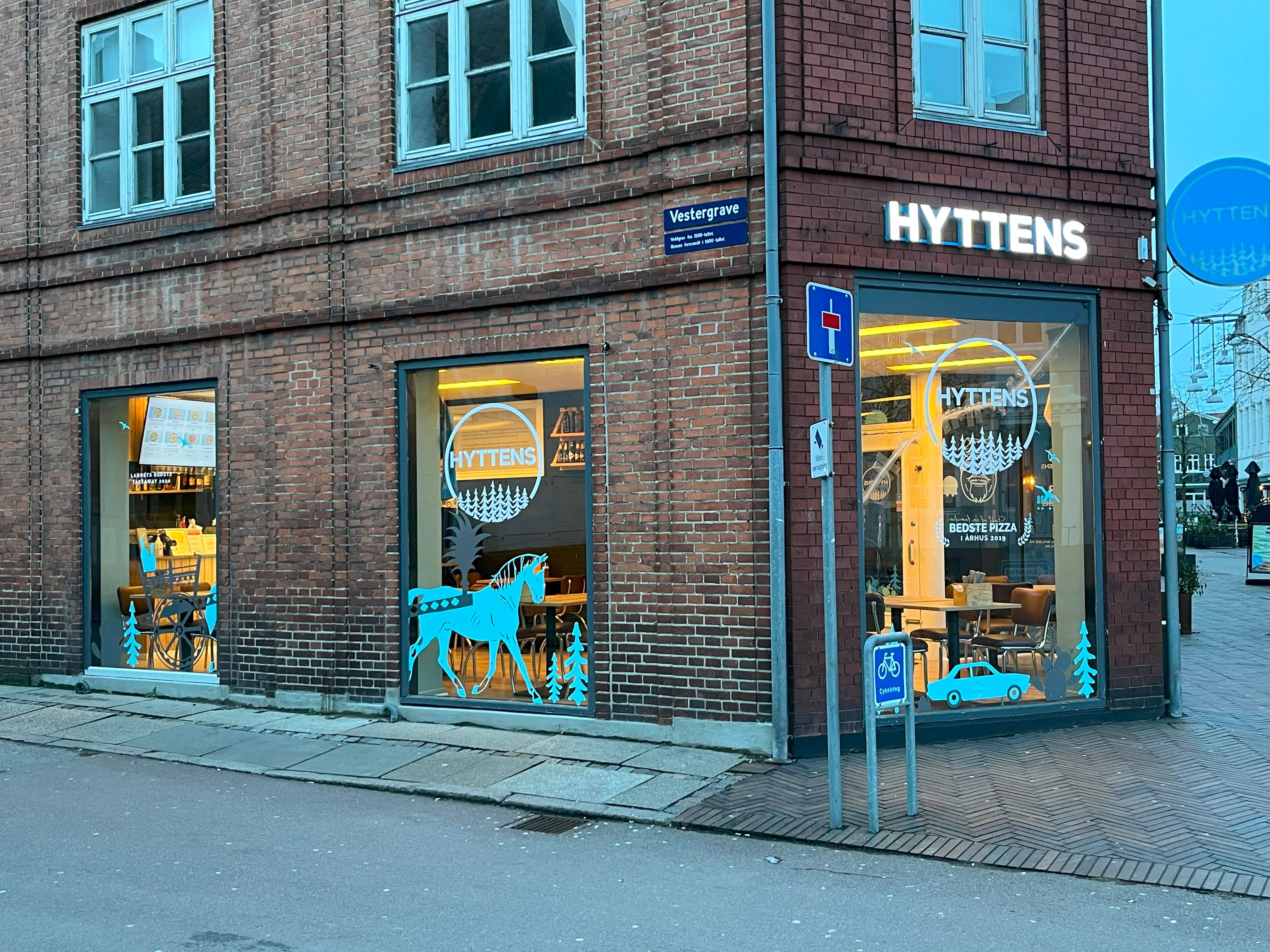 Hyttens pizzeria på Vestergade i Randers med vinduer og døre med hyggelige illustrationer og indvendige møbler og stole