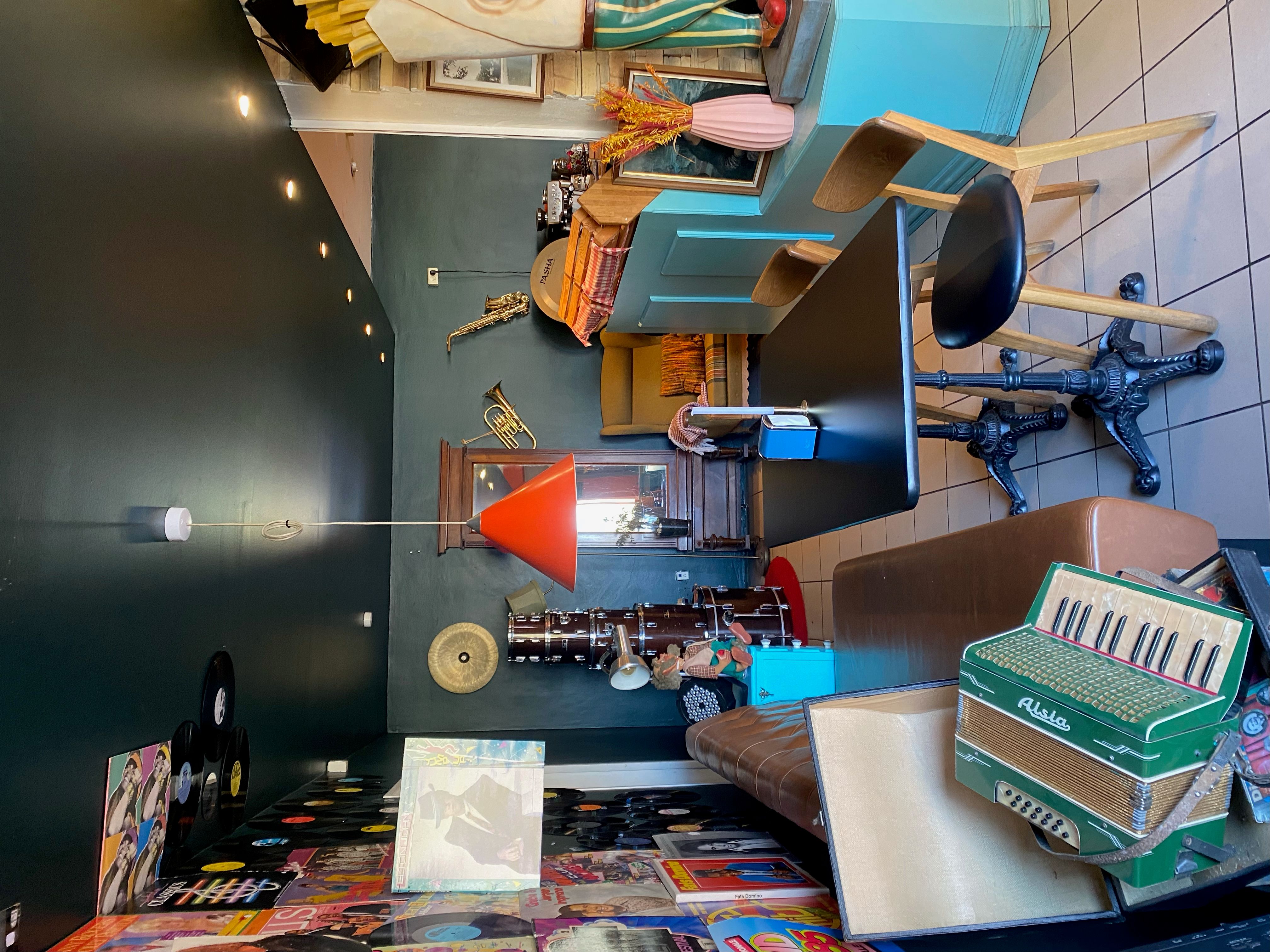 Dekorativ restaurant med borde og stole samt akustiske instrumenter og vinylplader