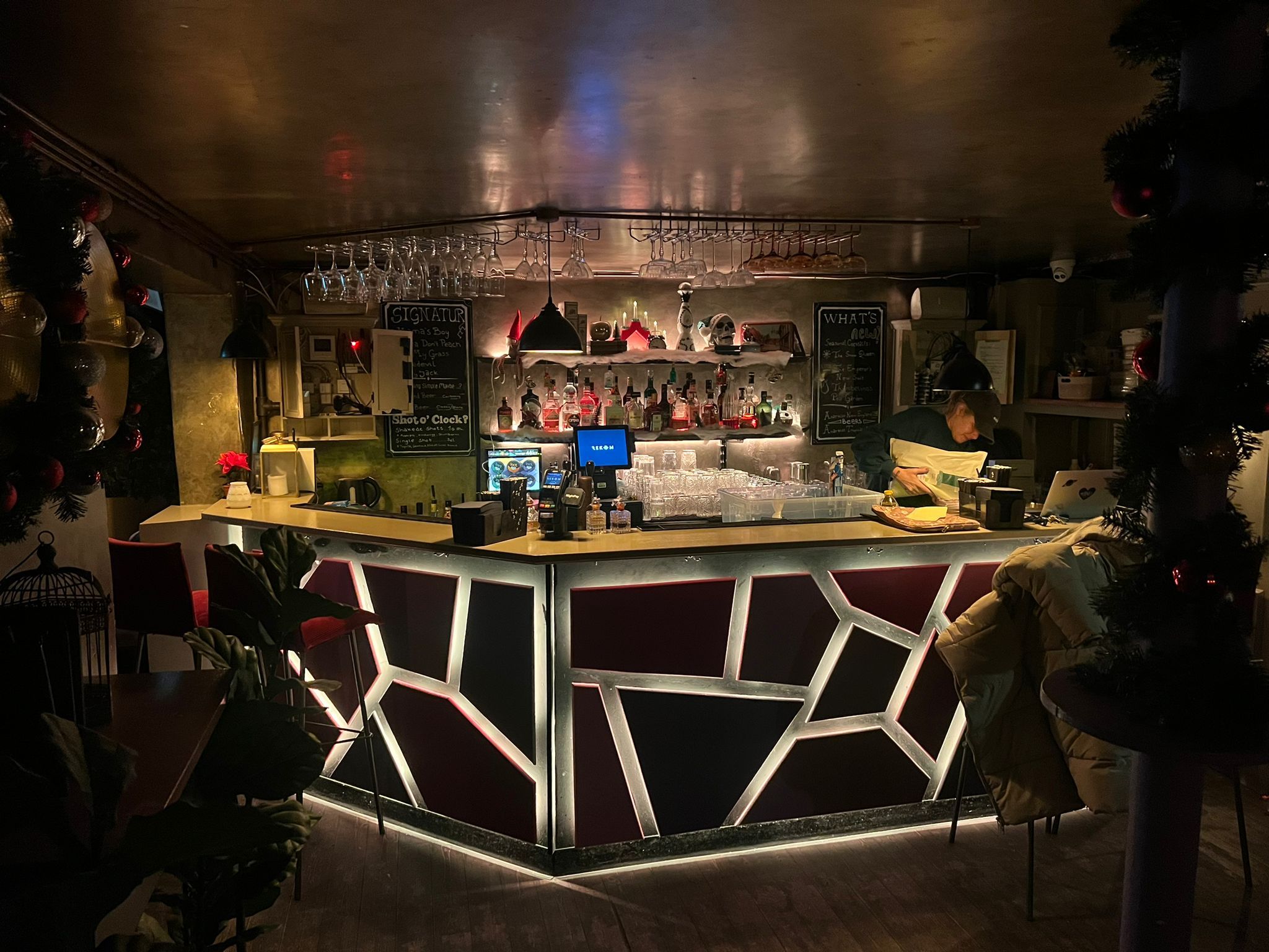 Københavns cocktailbar med røde stole og lyse accenter i baren samt juletræer og lysedekorationer