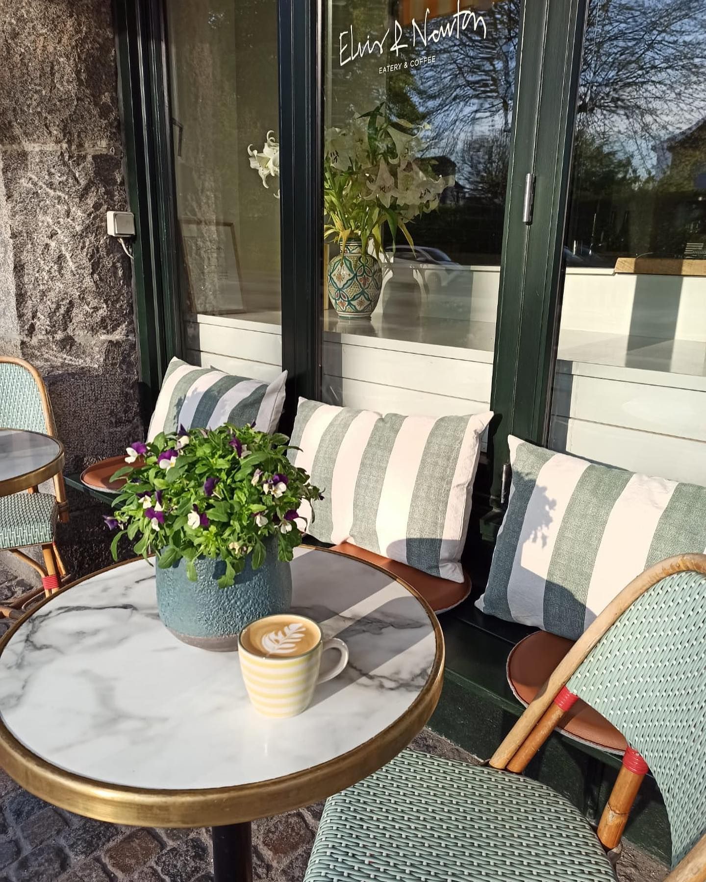 Caféen med elegant møbelsæt og marmorbord med blomster og en kop kaffe med kunstig lavning