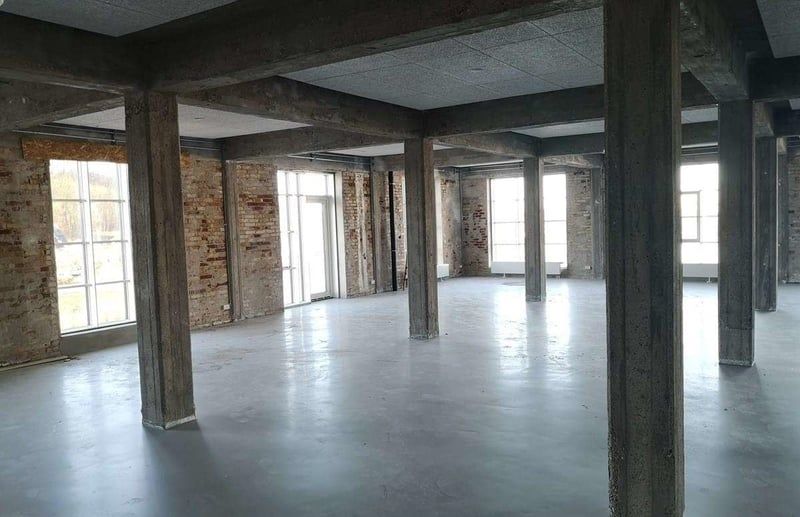 Rummeligt kontor med højt loft, stærke søjler og store vinduer for meget lys og en åben atmosfære