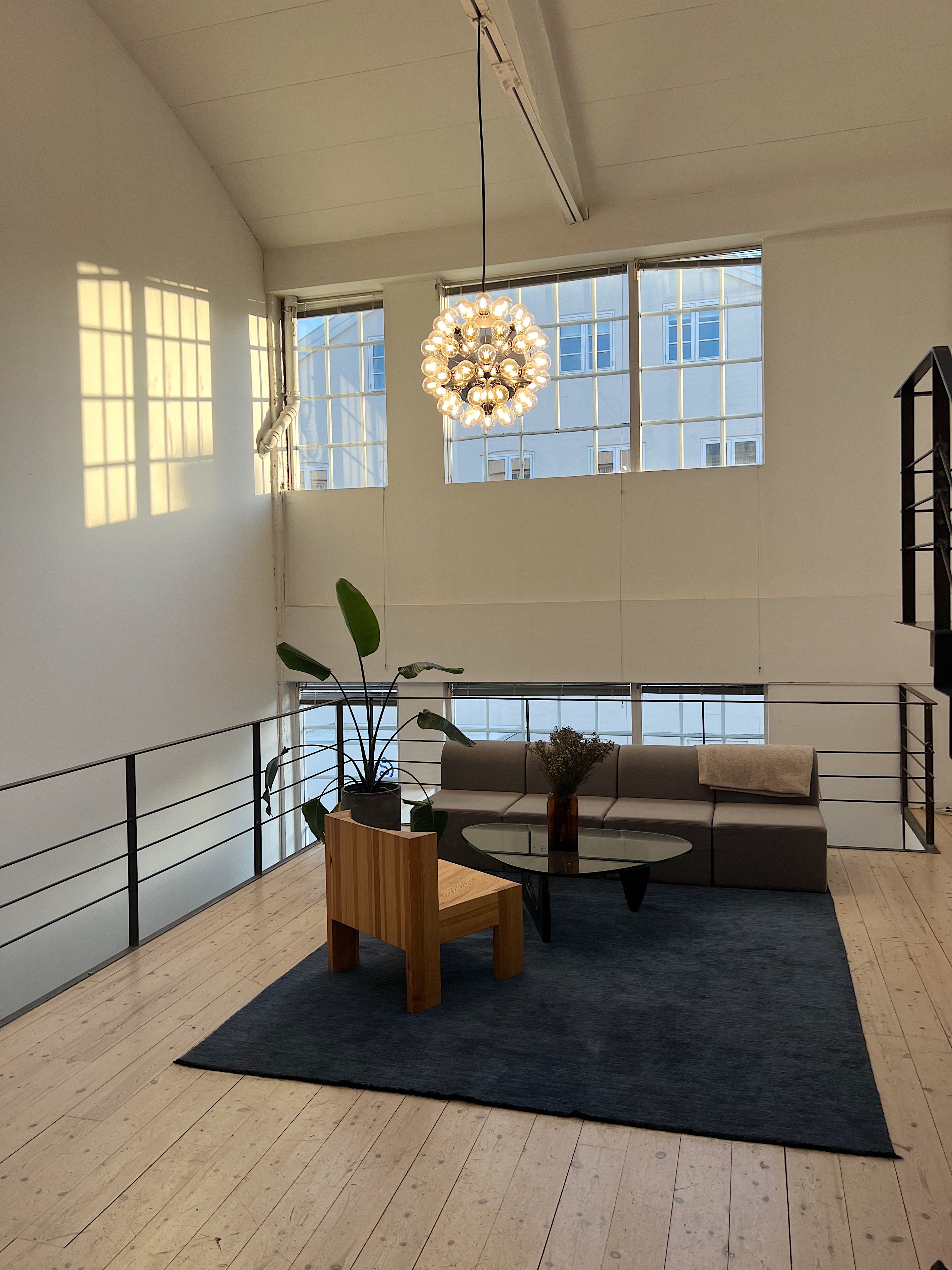 Et sofistikeret og moderne kontorlokal med lyse gulve, stort lys og flotte møbler