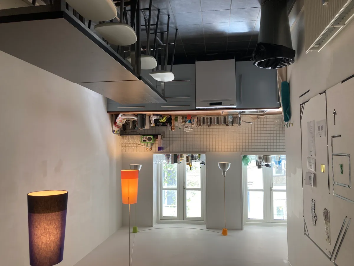 Kontorlokaler med højloft og loftsvinduer, lyse lamper og åbne ruder, der vender mod en grøn have