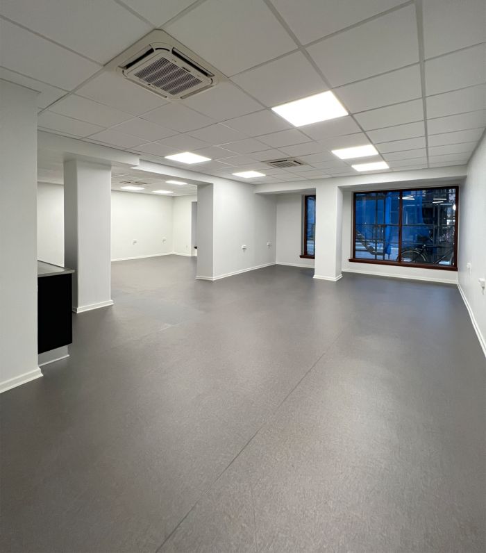 Et stort, tomt lokale med gulv og vægge i gråt, hvide loftsplader og indbygget klimaanlæg