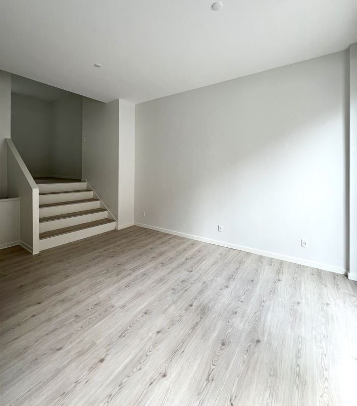 Her ses en stor lejlighed med et stort, gulvtæt gulv og hvide vægge, der skaber en åben og lyse atmosfære. Stairs er let at