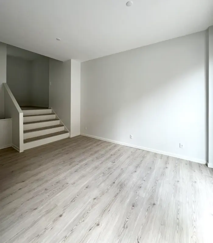 Her ses en stor lejlighed med et stort, gulvtæt gulv og hvide vægge, der skaber en åben og lyse atmosfære. Stairs er let at