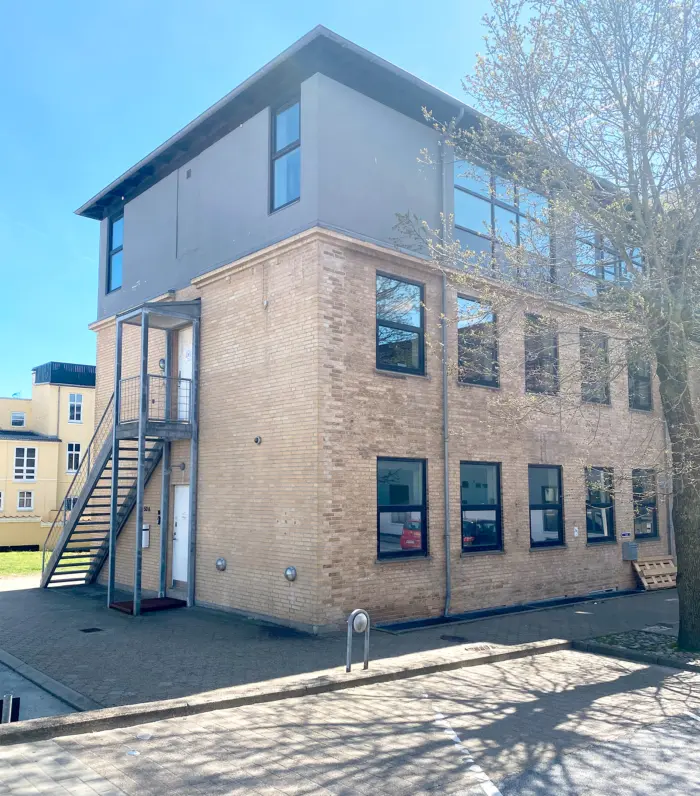 Et moderne lejlighedshus med fire etager i Hjørring. Huset har store, lyse ruder og en glasdør. Et skrånende trappeløb fører