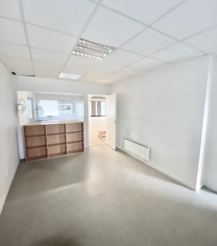 En tom rum med hvide vægge og loft samt lyse gulv og et træskab. Der er også en åben dør til et andet rum.