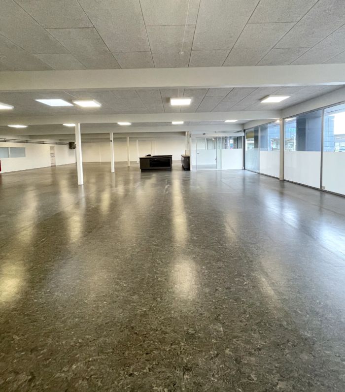 Indvendigt i en stor hall med marmorgulv og hvide vægge samt glasvinduer mod gaden og flere hvide søjler