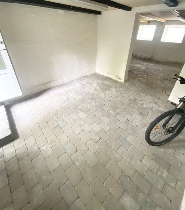 Det værelse med lysegulle vægge og bjælkeloft har udvendige vinduer og nyt stengulv til opbevaring og hobby