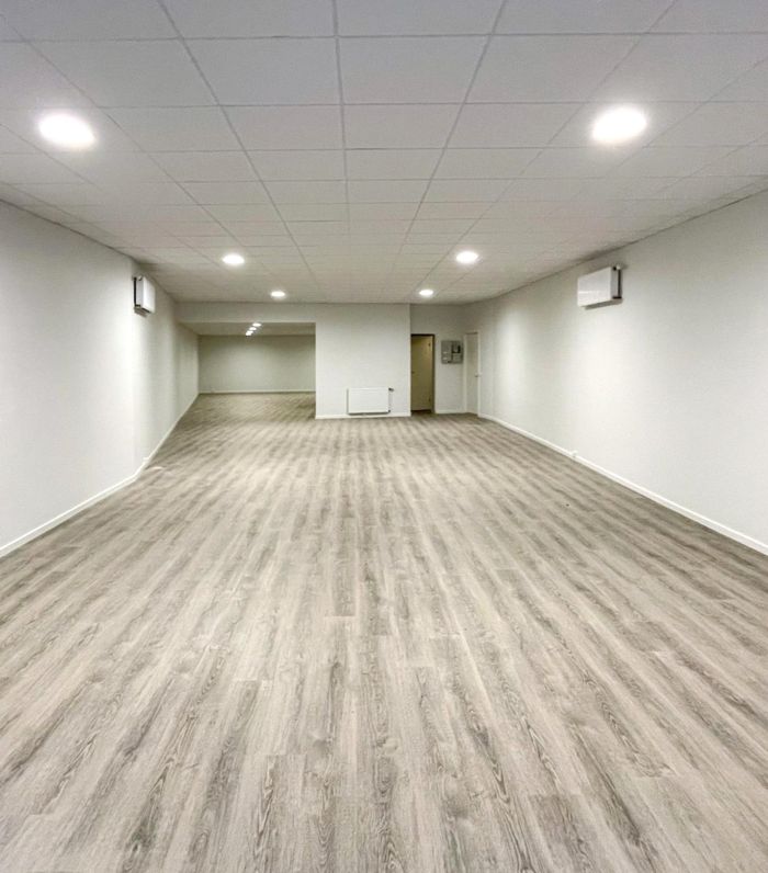 Langt og bredt forretningslokale med hvidt loft og vægge samt trægulv, som er nyrenoveret og færdig til brug.