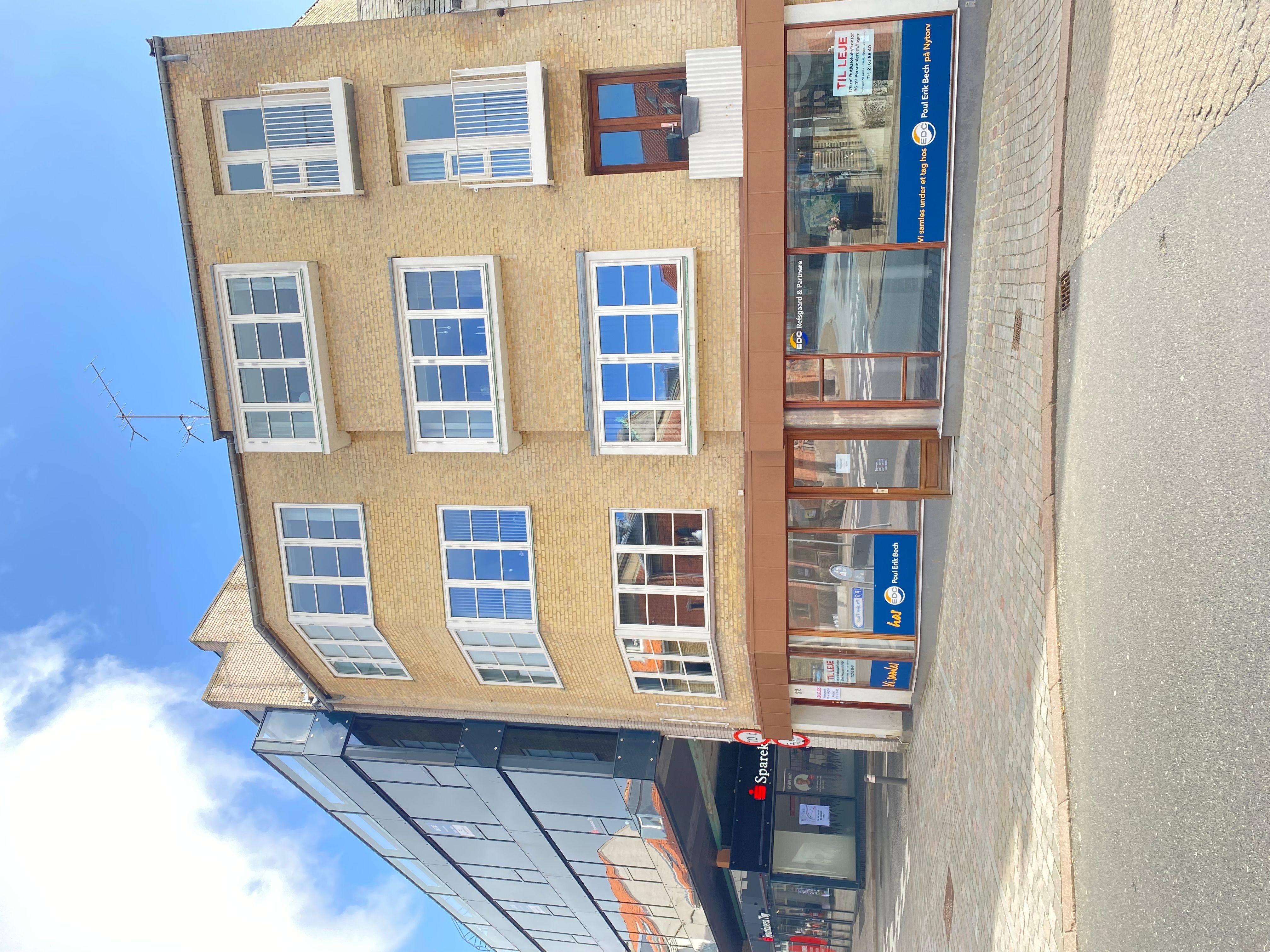 Erhvervslejemål med lyse vinduespartier og mærkeskilt i Viborgs centrum. Lejligheder og forretninger med fin udsigt over