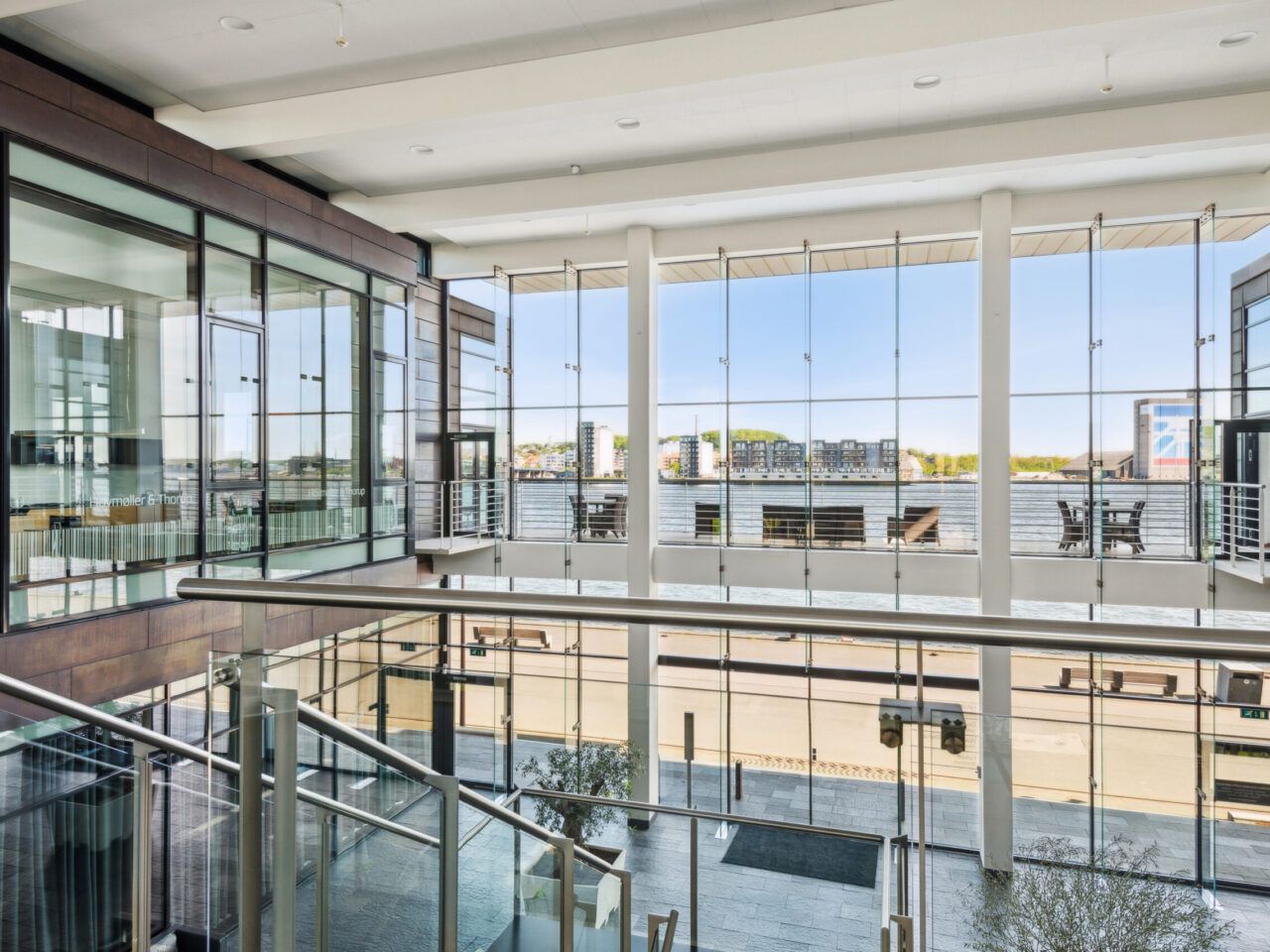 Glasvinduer med udsigt til vandet og havneområdet. Højloftede lokaler med moderne interiør og lyse møbler. Et terrasseområde