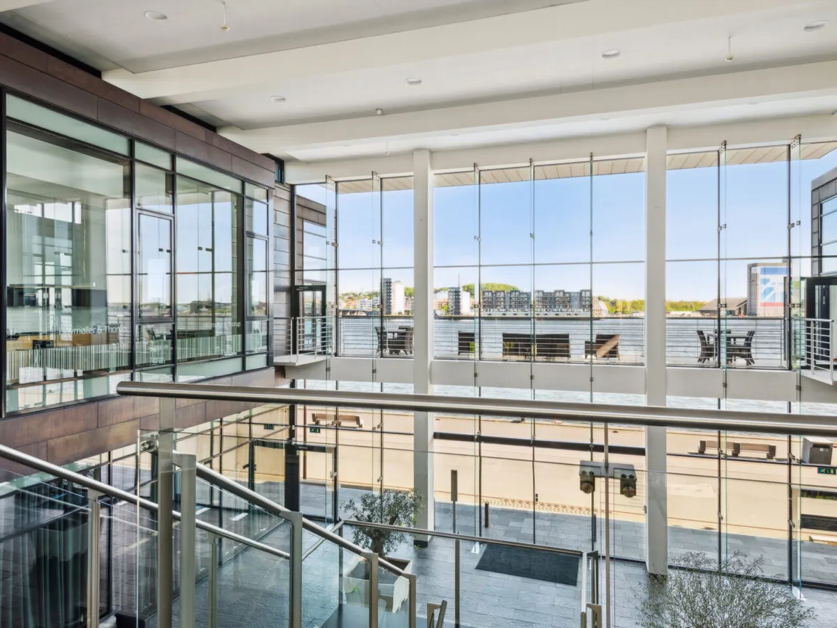 Glasvinduer med udsigt til vandet og havneområdet. Højloftede lokaler med moderne interiør og lyse møbler. Et terrasseområde