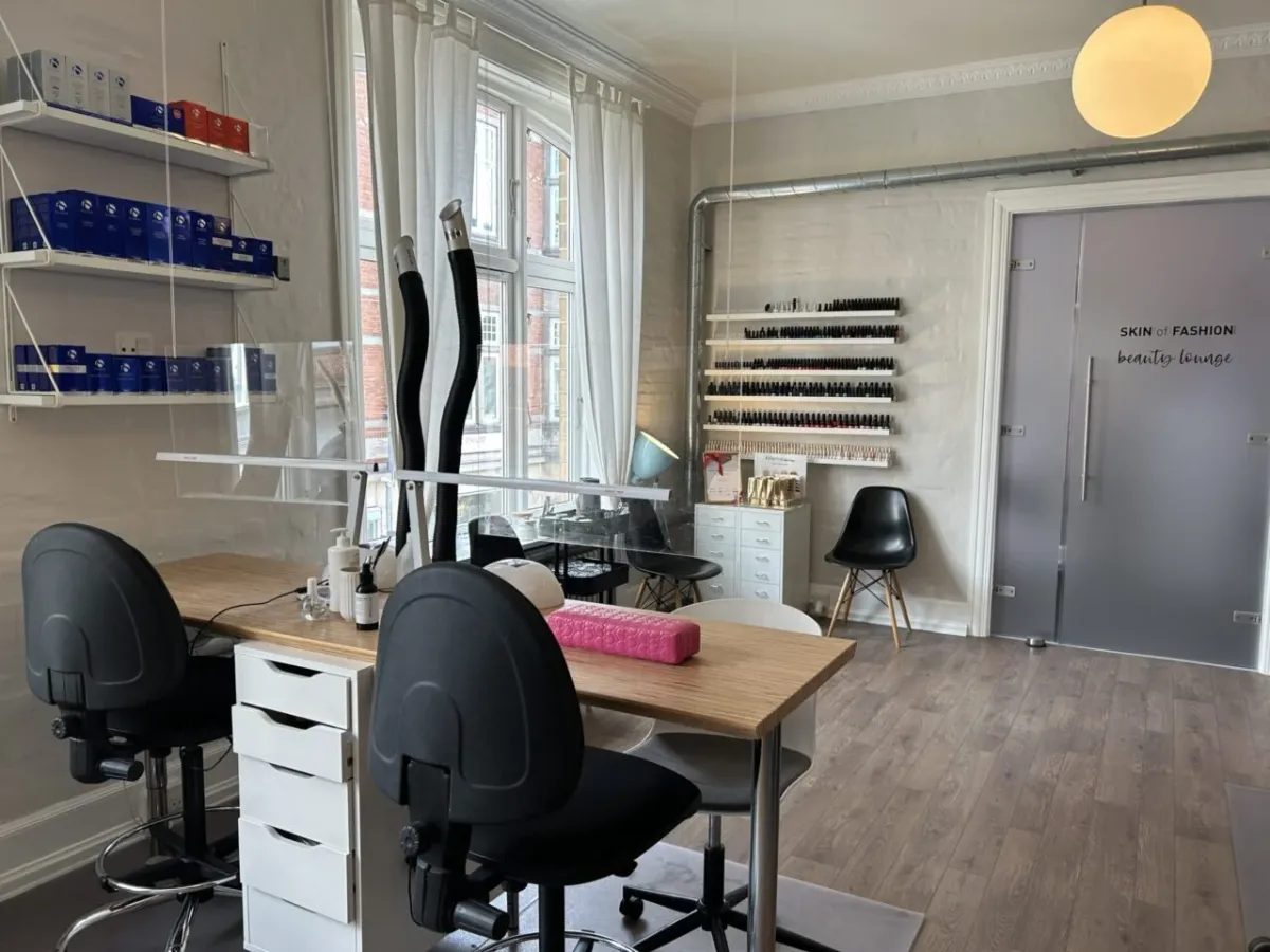 Foto af en salon med møbler og udstyr til skønhedsbehandlinger, hvor der er stolpelampe og to stole i sort og hvid