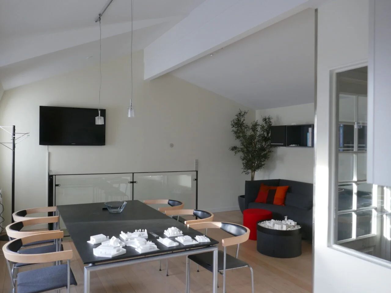 Moderne møbler og teksturer i loftet i et luksuriøst og minimalistisk studieloft med en stor sofa og en fjernsynsskærm