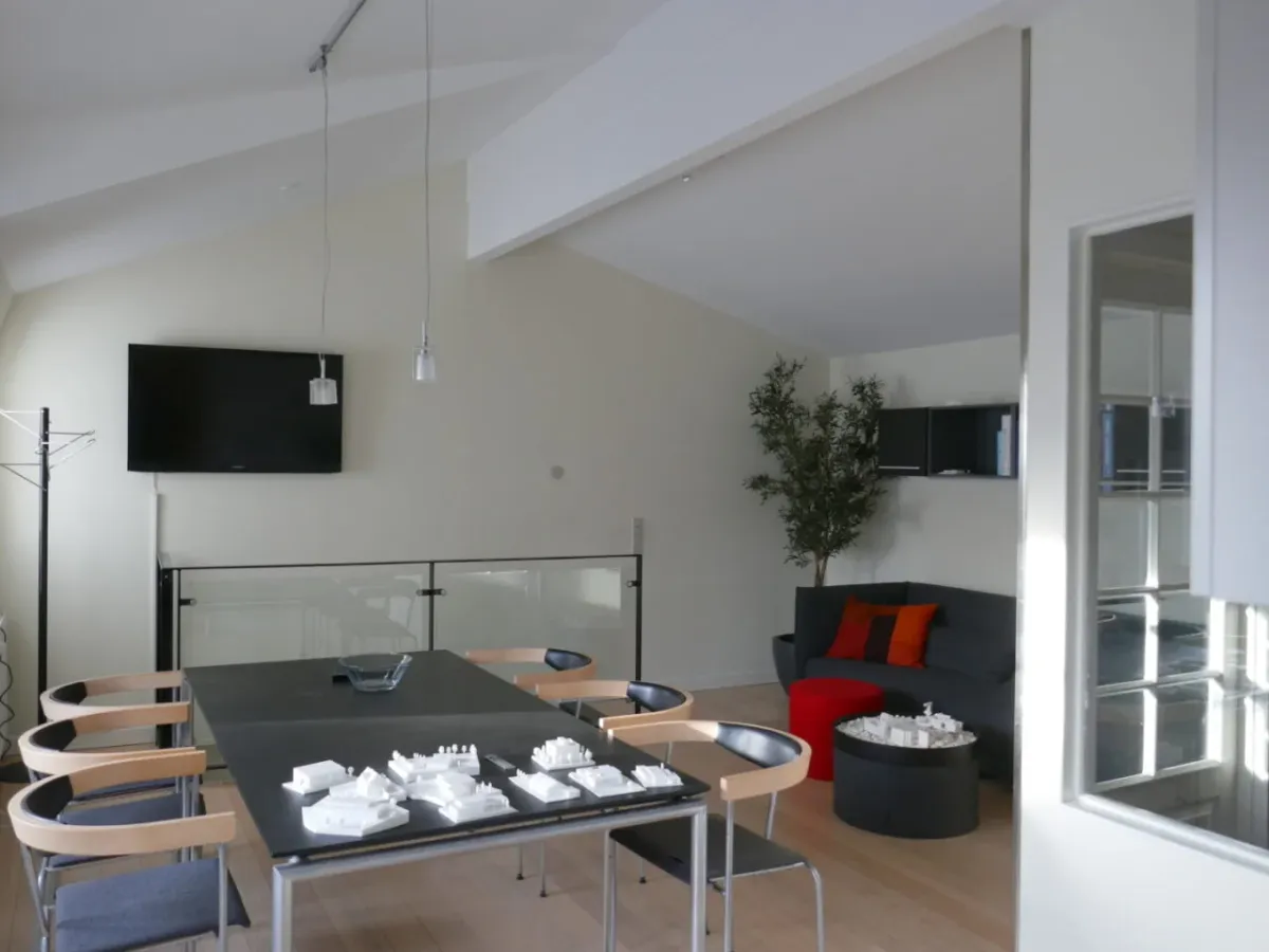 Moderne møbler og teksturer i loftet i et luksuriøst og minimalistisk studieloft med en stor sofa og en fjernsynsskærm