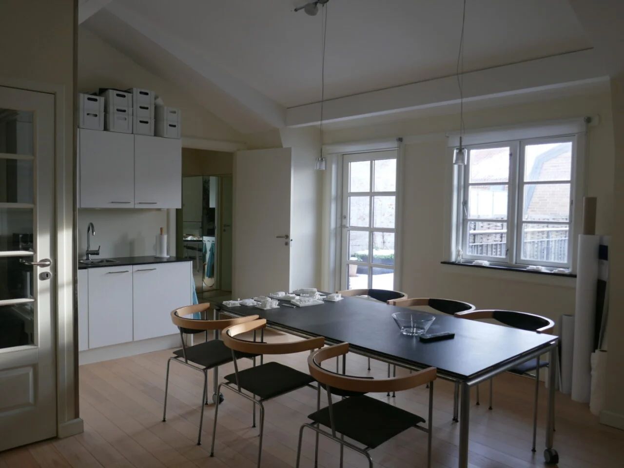 Moderne køkken med højloft, lysevinduer, højloftsvinduer og massivt trægulv. Vægge og møbler er hvide, og der er en