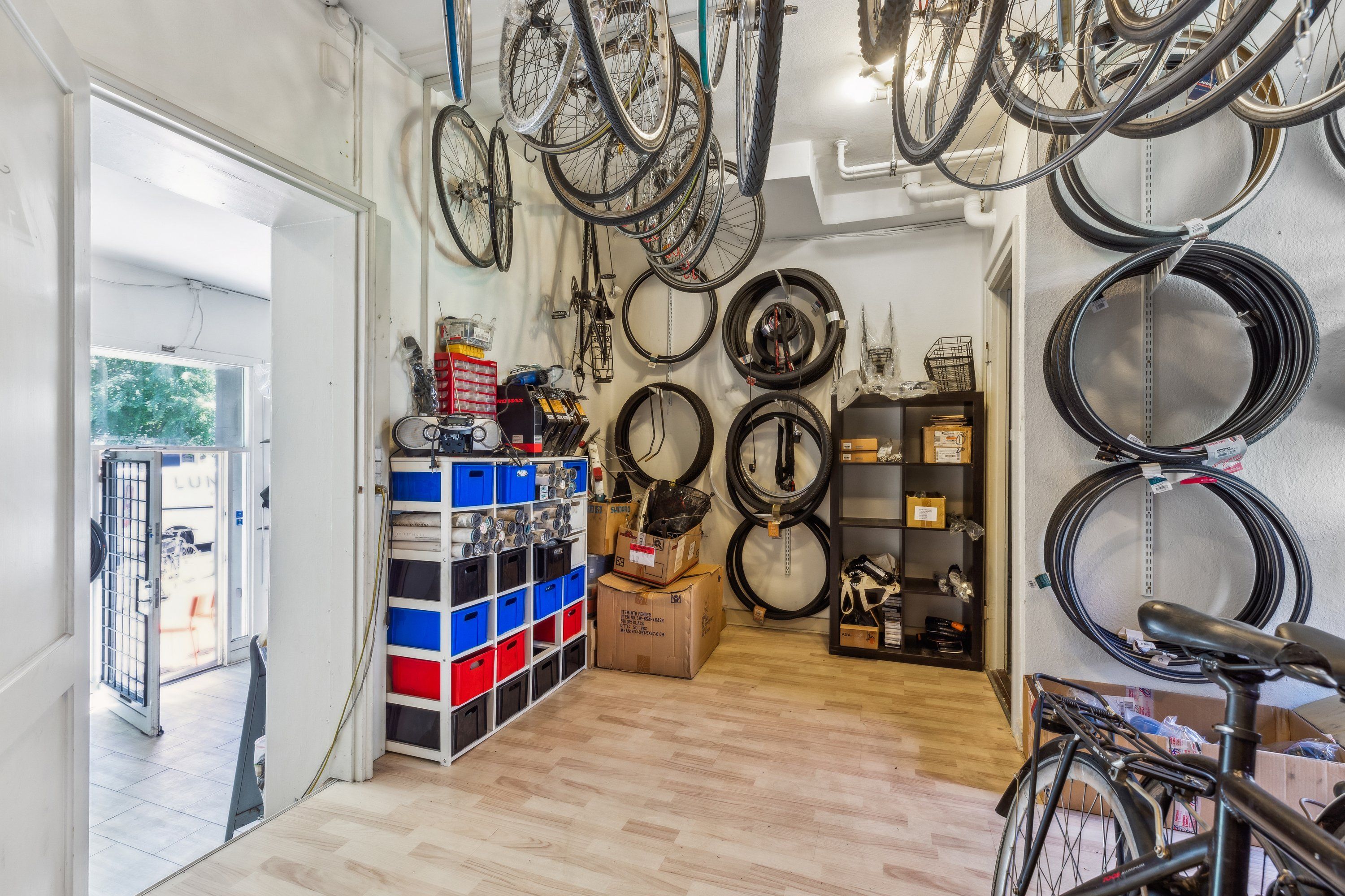 Erhvervslokale med flere cykler og diverse lagermateriale, hjul og kasser på loftet og gulvet