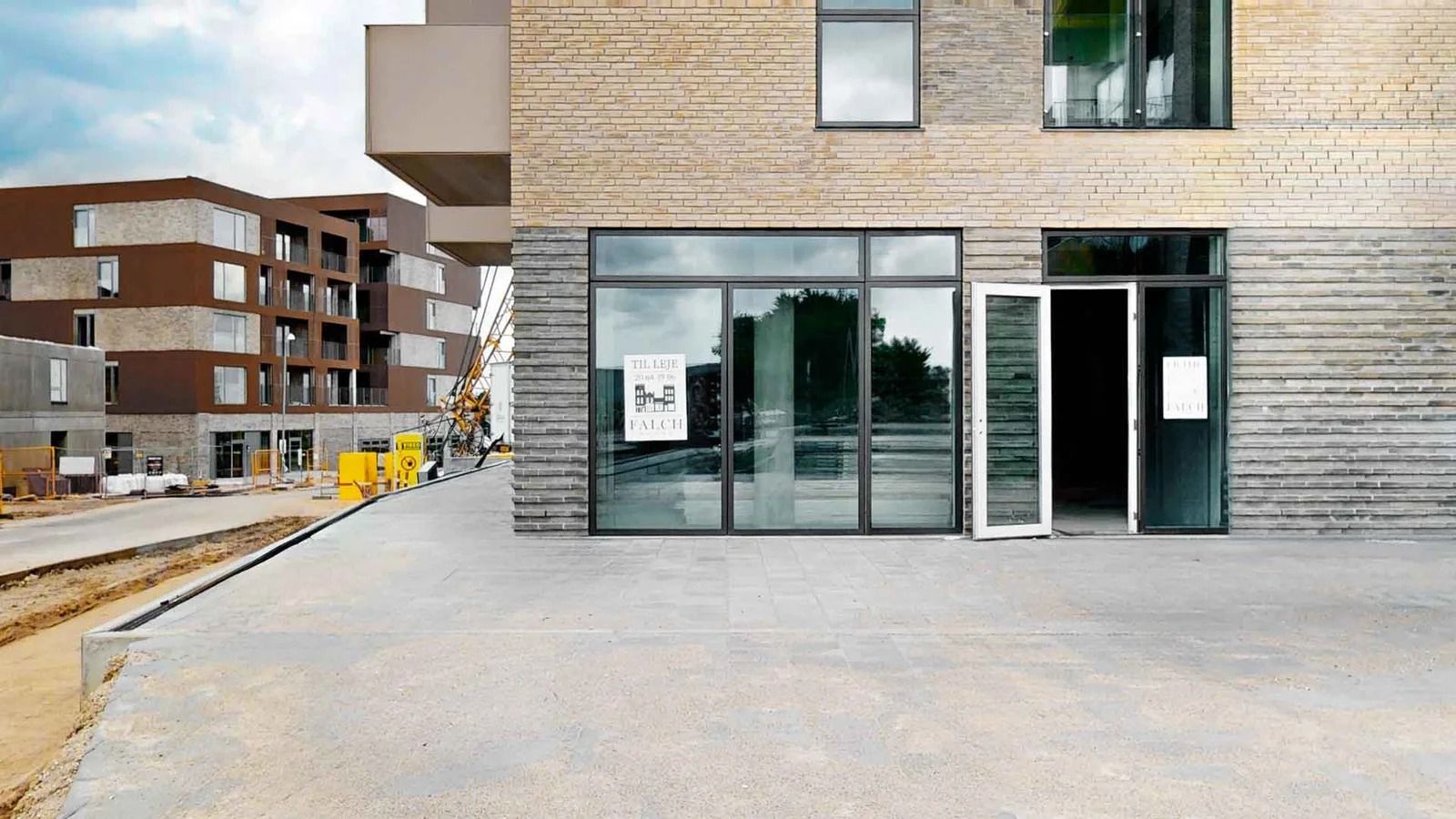 En nybygget bygning med glasruder og en åben dør, der fører til indgangen