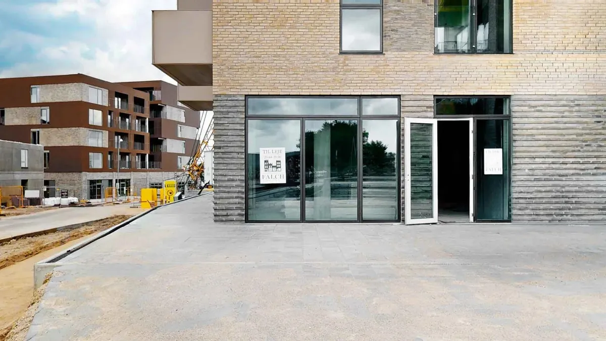 En nybygget bygning med glasruder og en åben dør, der fører til indgangen