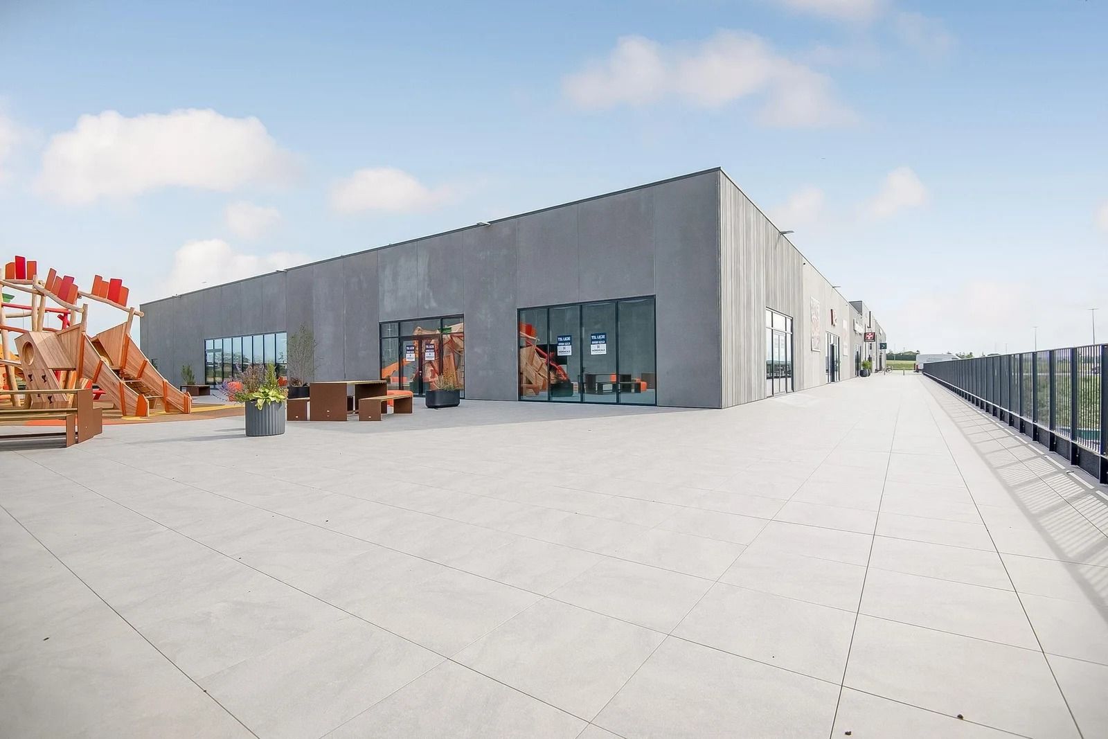 Et moderne bygning med glasruder, en udsigt over hvidt gulv og smukke planter i potter langs siden af bygningen