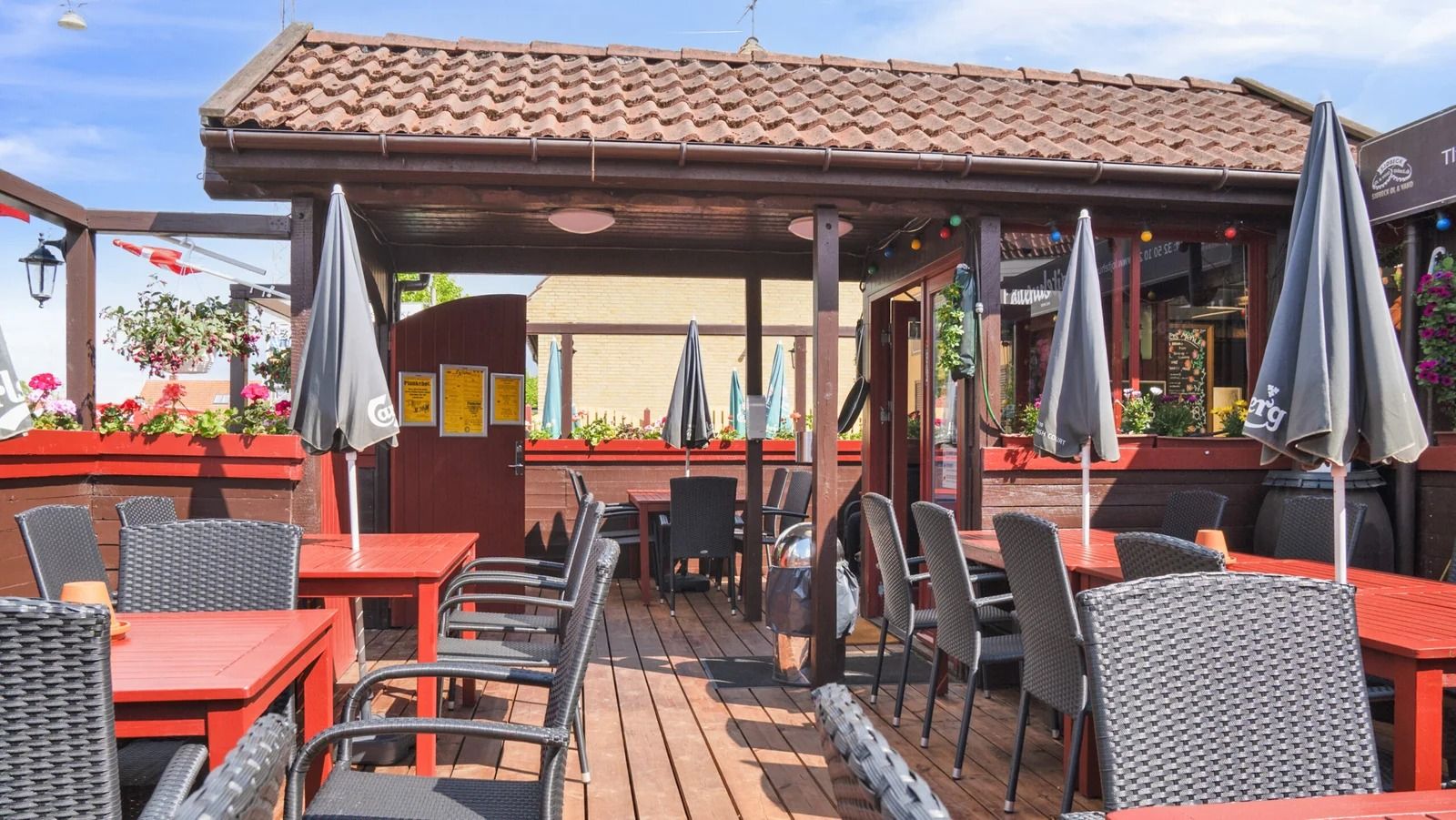 En udendørs terrasse med borde og stole og parasoller i en lille by i Danmark