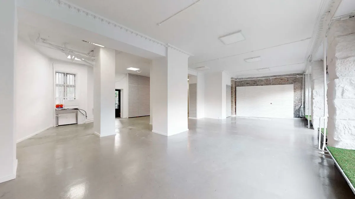 Et hus med hvide vægge og gulv, høje søjler og garageport, der er åben for gårdspladsen