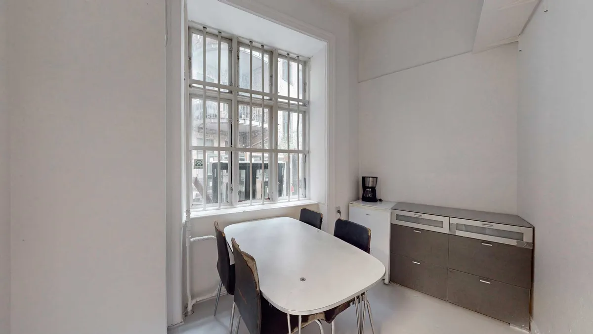 Et hvidt køkken med spisestue og møbler og en kaffemaskine på et højt bord