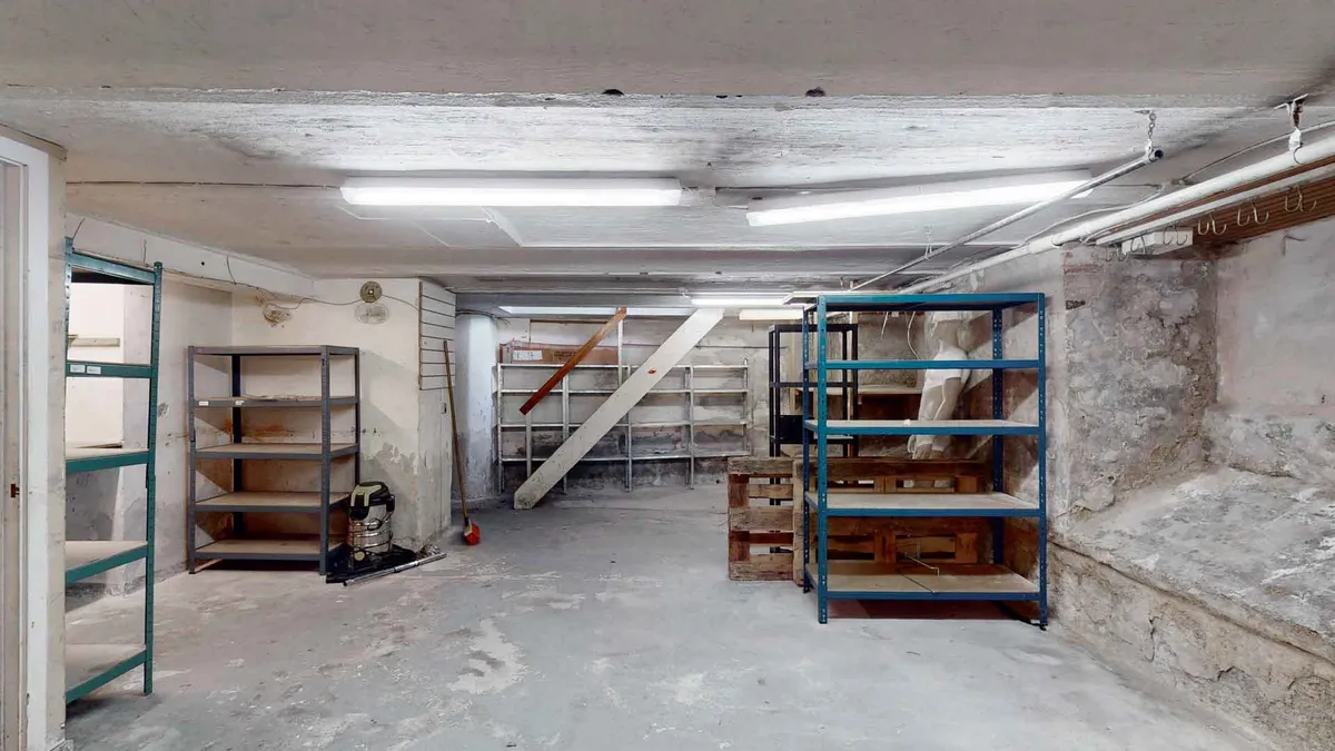 En gammel, renoveringsvenlig erhvervslejlighed med et stort lager, to vindtrapper og en møbleret stue