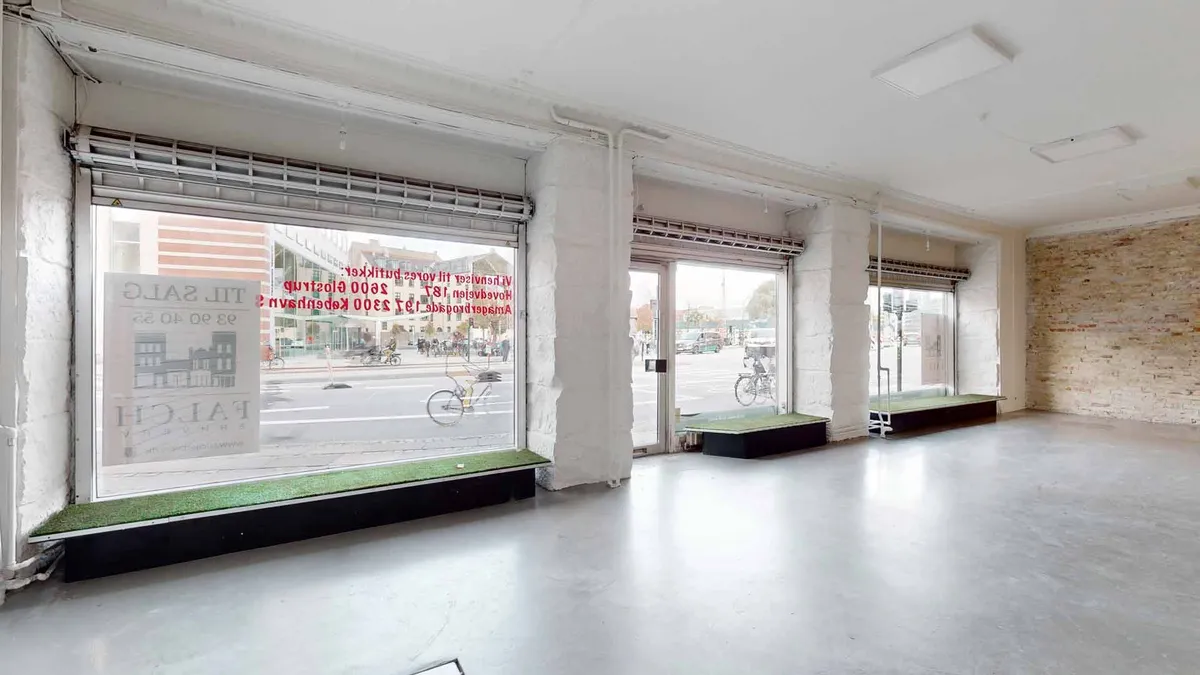 Moderne, lyse lokaler med glasvinduer og indvendige ruder, åbne og tømme, med kunstværk på vinduet og grønne plantefelter