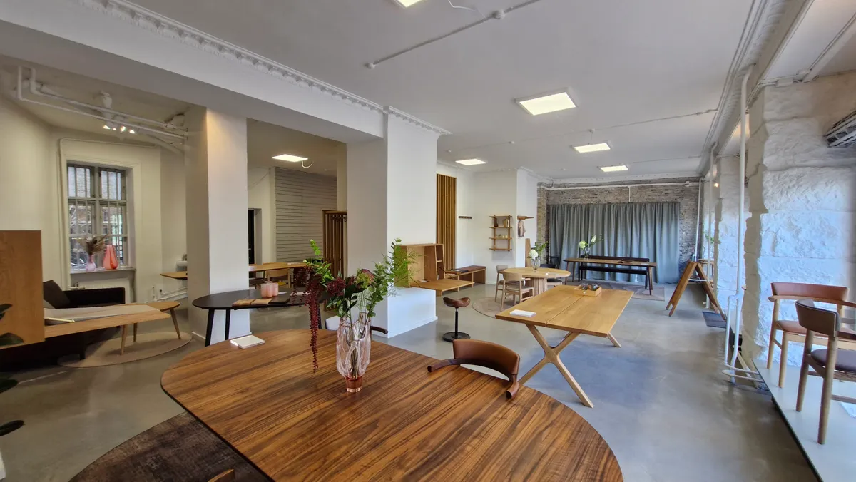 Elegant indretning med træborde og stole, hvide vægge og lyse loftslamper, møbler og kunstværker, moderne interiør med