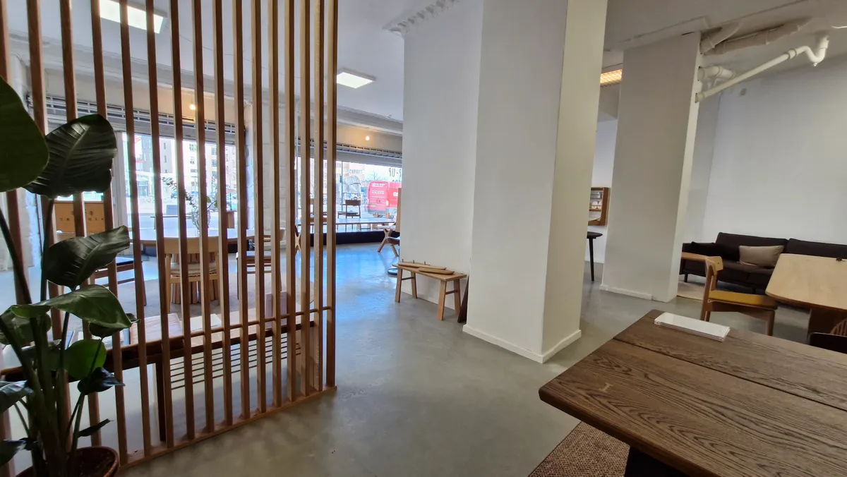 Moderne indretning med lyse, trægulve og store vinduer, udstyret med borde og stole og møbler.