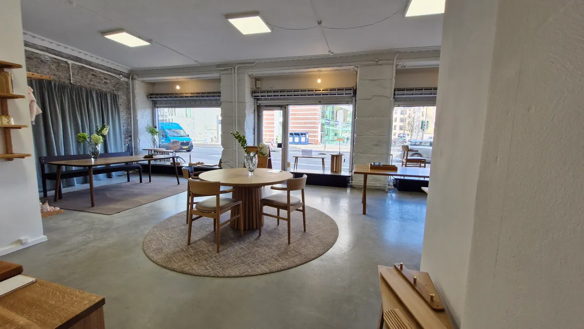 Møbelforretning med runde bord og stole, lysekroner og store ruder med udsigt til gade